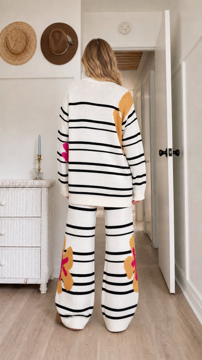 Back view of model wearing relaxed white striped knit sweater and matching wide-leg trousers