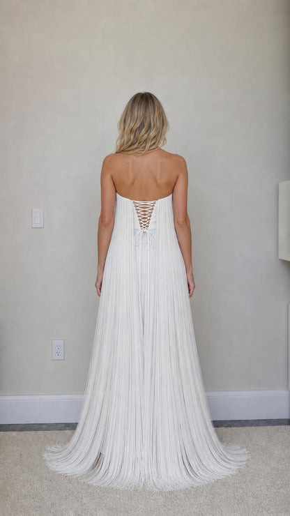 Back view showing lace-up corset detail on white fringe dress
