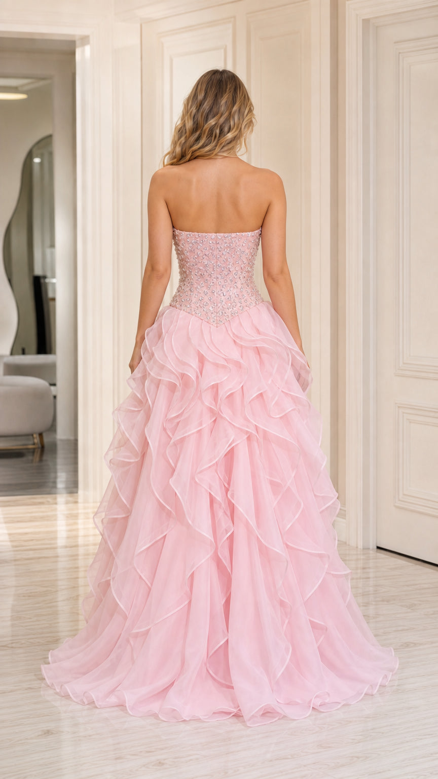 Back view of model wearing baby pink strapless tiered ruffle evening gown