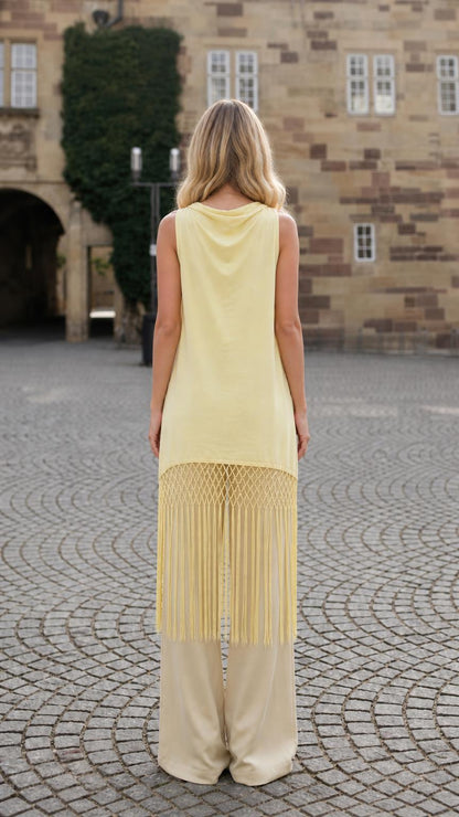 Back view of model showcasing draped cowl neck and long fringe hem