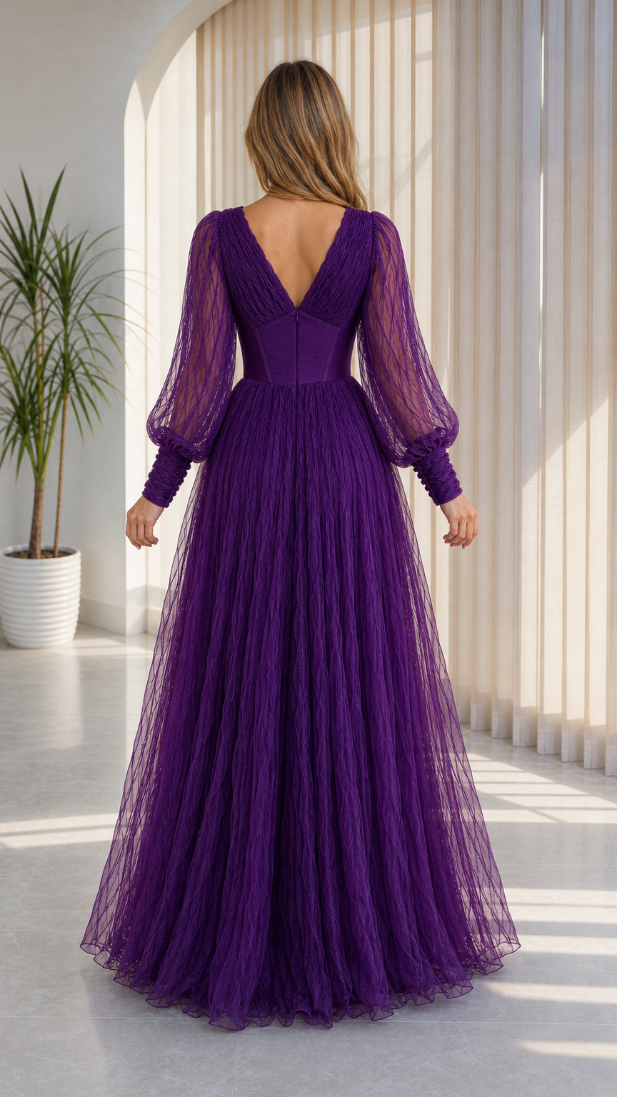 Back view of model wearing purple V-neck evening gown with flowing skirt