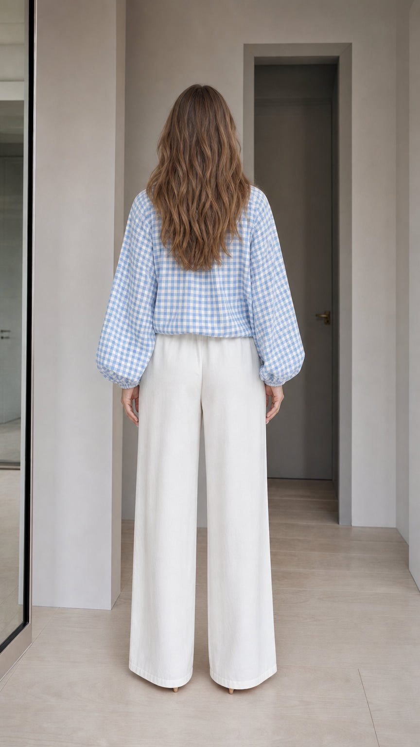 Woman wearing light blue gingham check blouse, back view