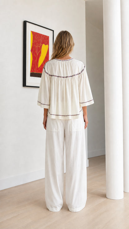 Back view of off-white embroidered peasant blouse showing gathered yoke and relaxed fit