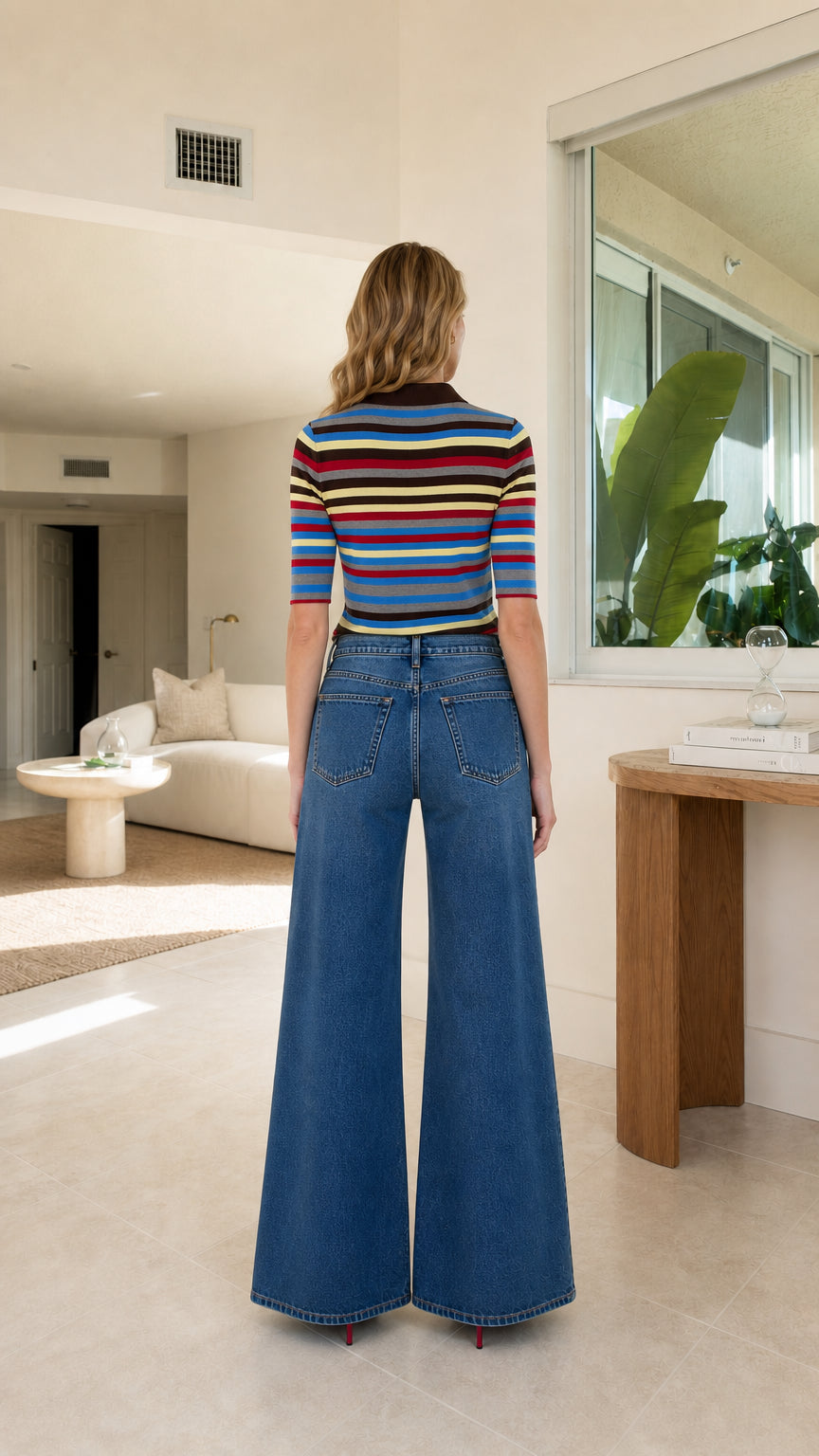 Back view of model wearing striped knit polo shirt and wide leg denim