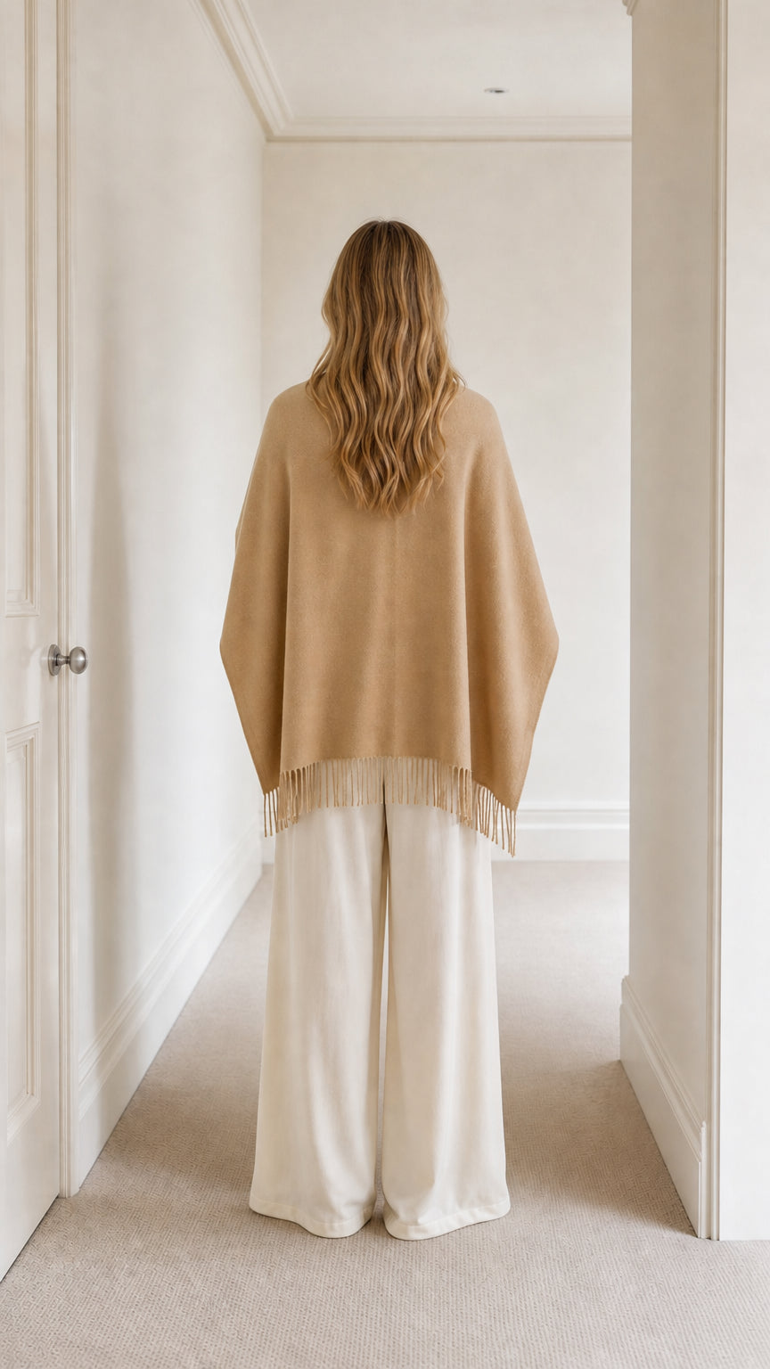 Back view of model showing camel fringed cape overlay and cream wide-leg pants