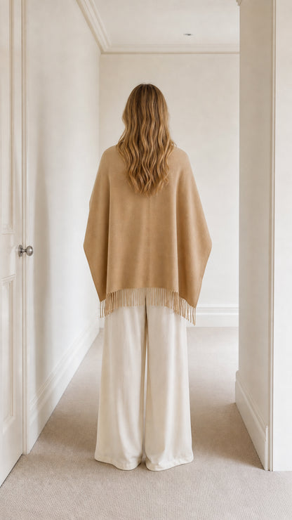 Back view of model showing camel fringed cape overlay and cream wide-leg pants