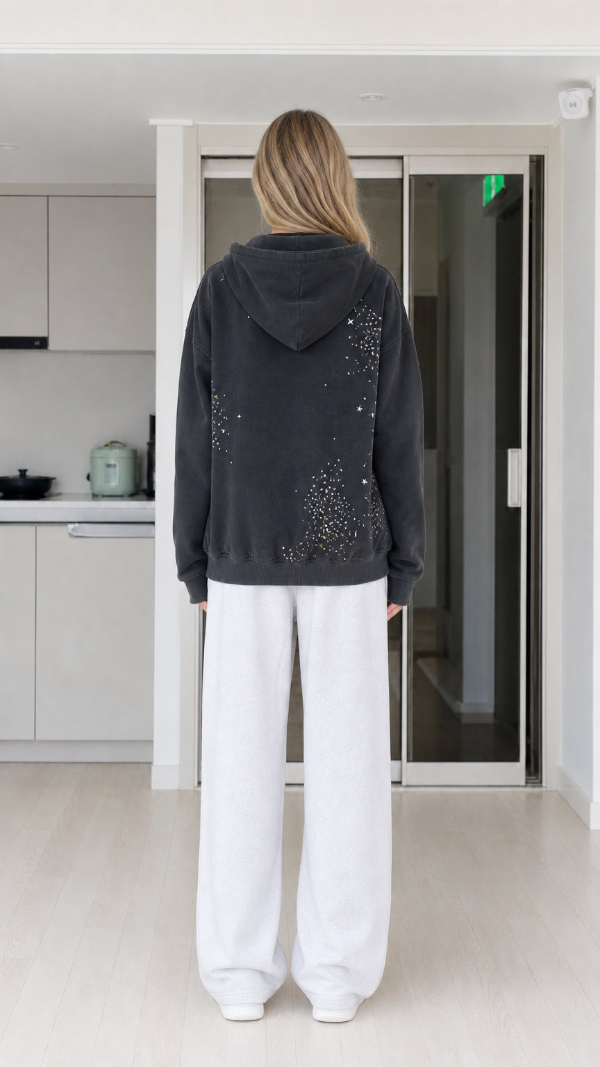 Back view of woman showing scattered rhinestone detail on washed black hoodie