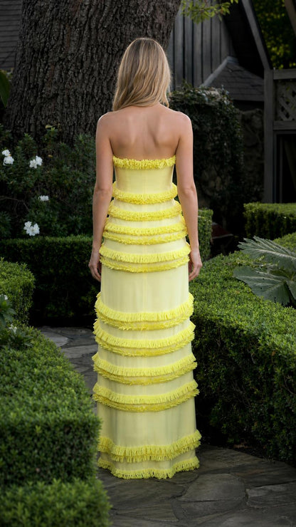 Model wearing yellow tiered fringe strapless maxi dress from back view