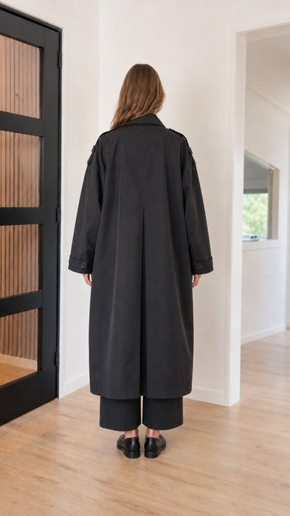 Back view of black maxi trench coat showing inverted pleat detail