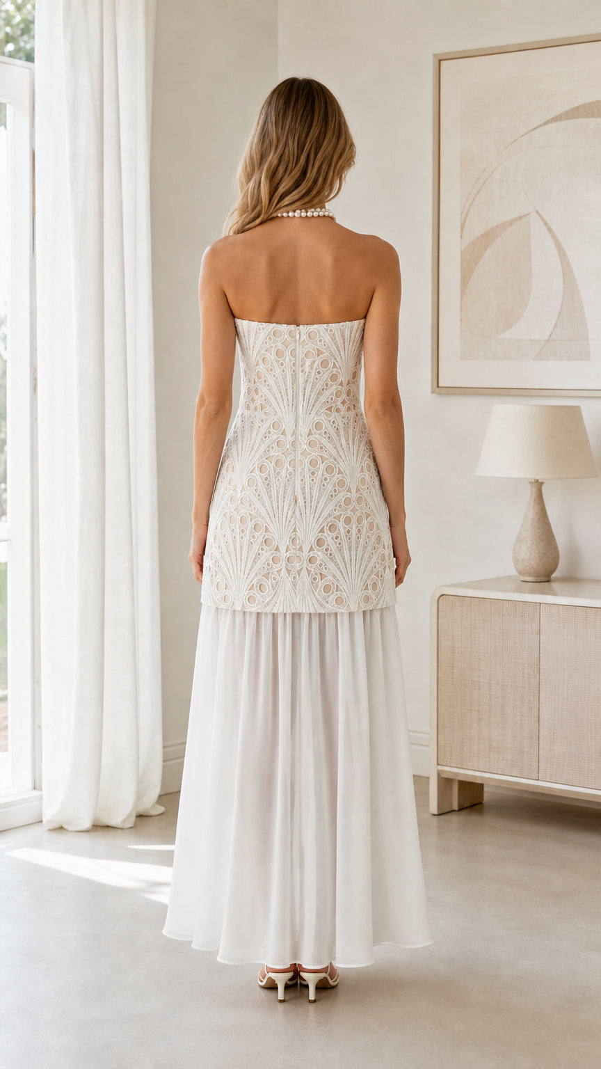 Back view of model wearing white strapless embroidered drop waist formal dress