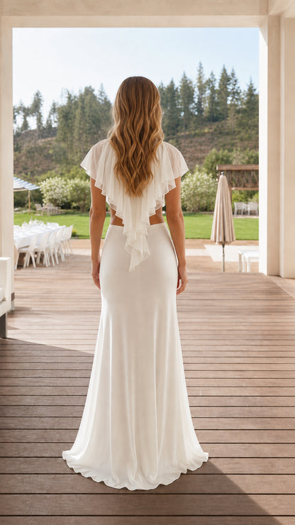 Back view of model wearing white two-piece ruffled crop top and floor-length skirt