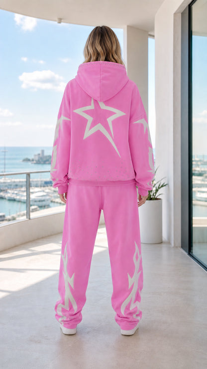 Back view of model showing large white star graphic on pink hoodie and sweatpants