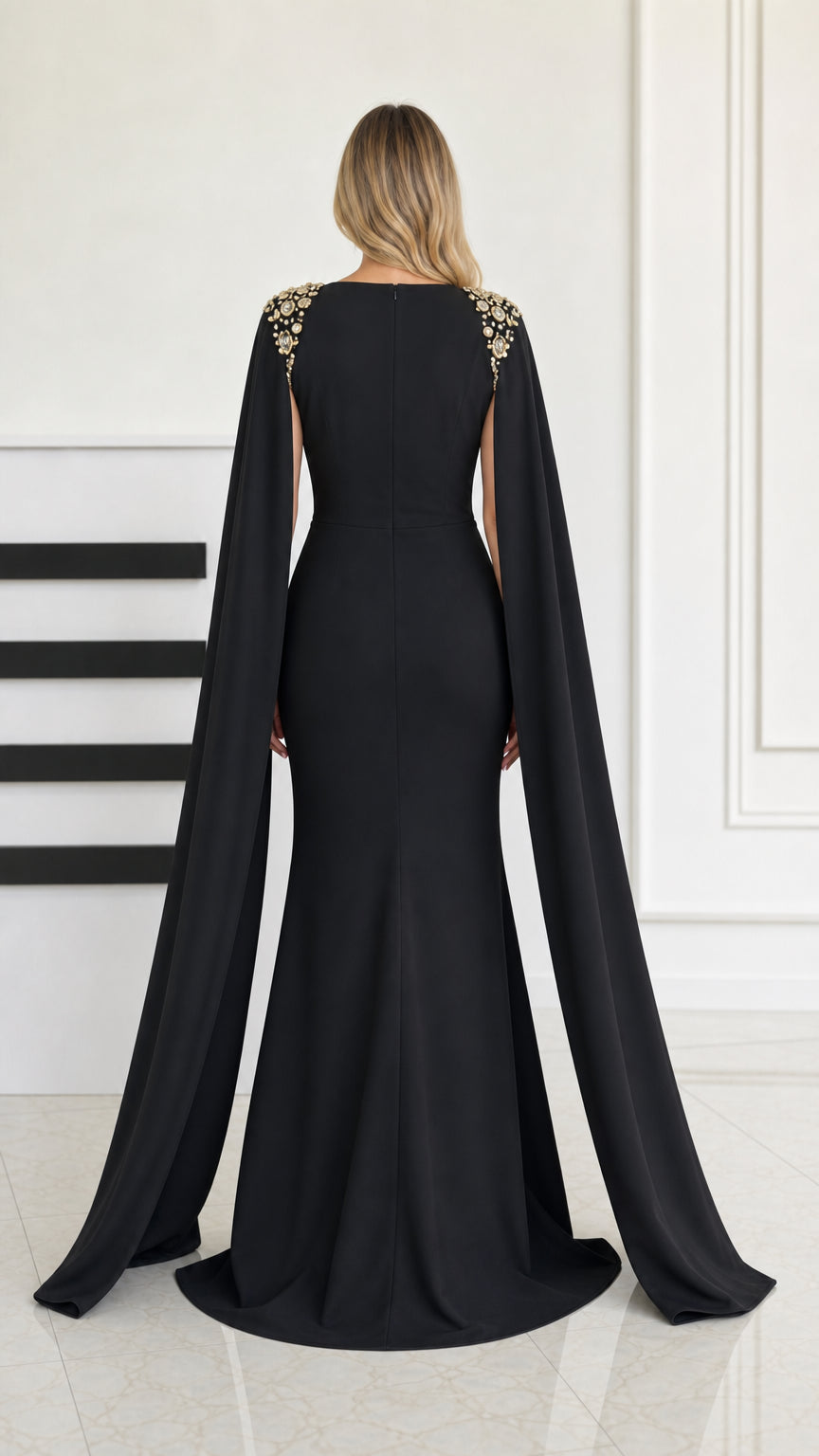 Back view of black formal mermaid gown featuring trailing cape sleeves