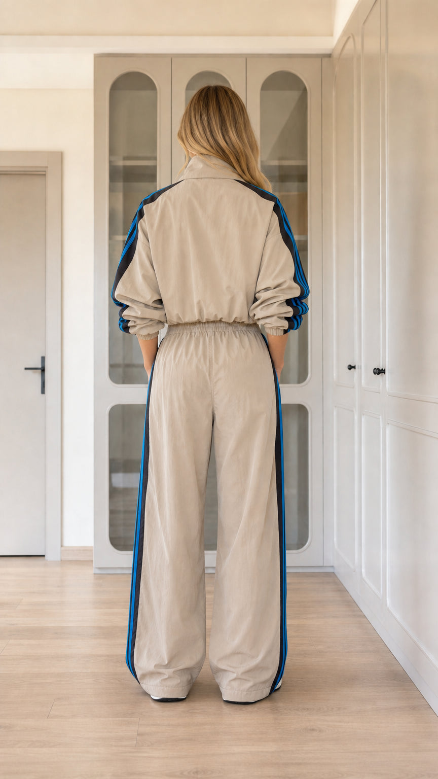 Back view of model wearing khaki tan cropped jacket and wide-leg track pants set