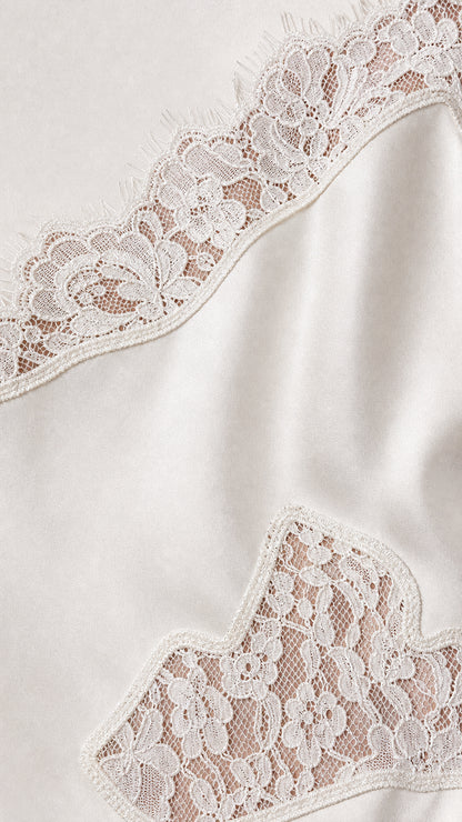 Close-up detail of white lace trim on satin fabric
