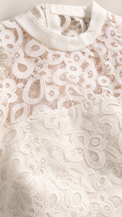 Close-up detail of white floral lace texture and round neckline trim