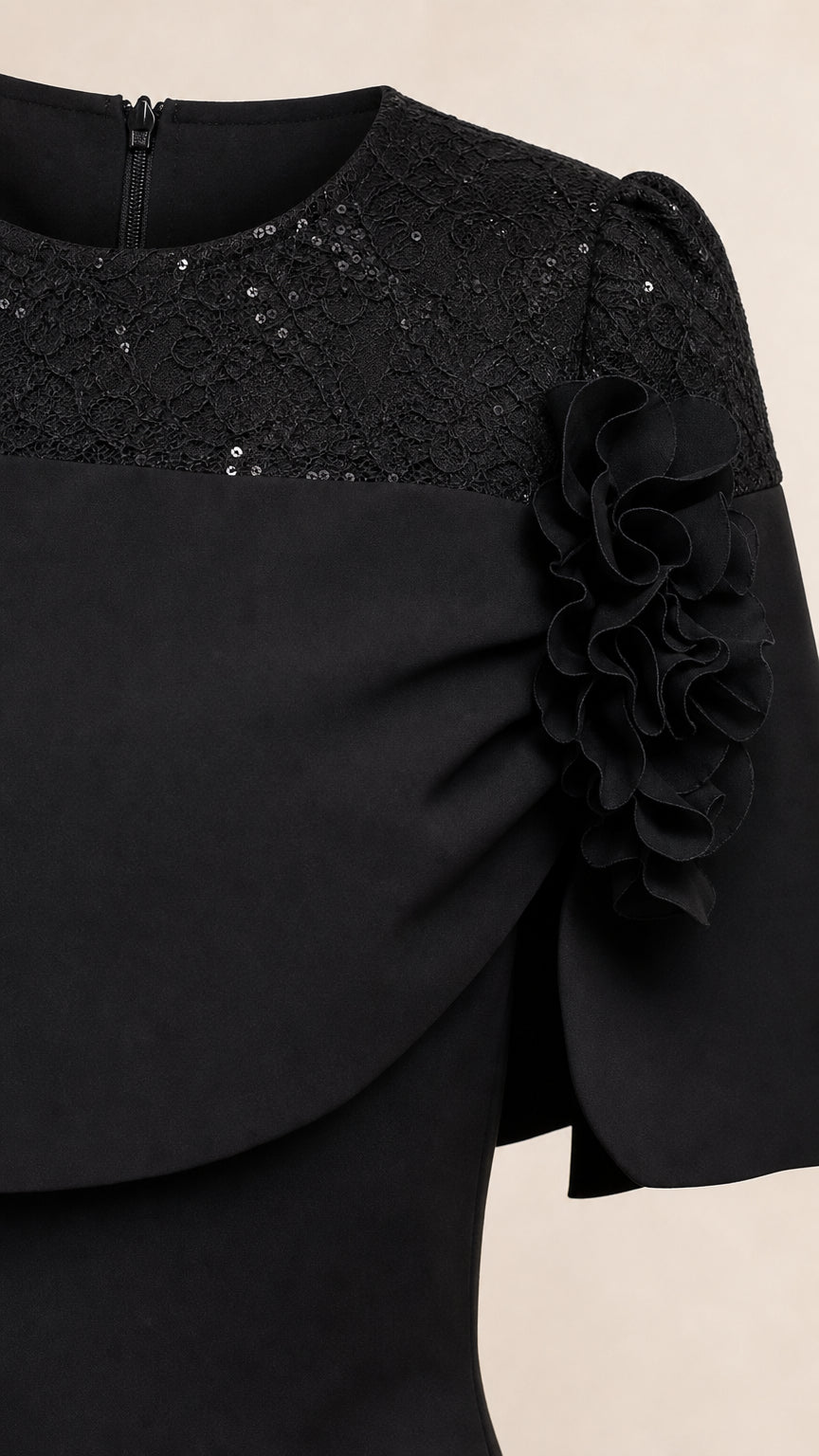 Close-up detail of black dress bodice showing sequin lace and floral applique