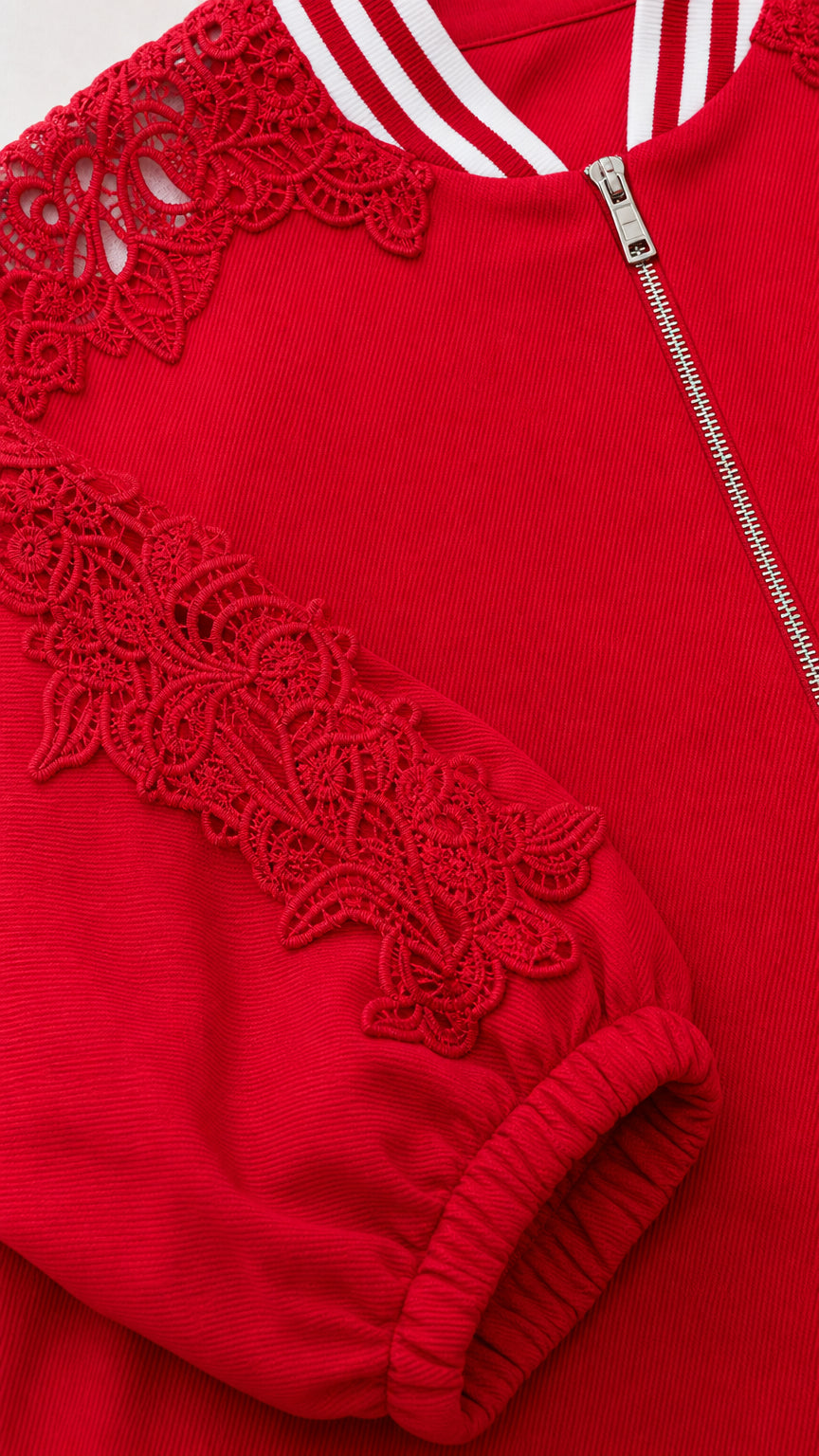 Close-up detail of red floral lace appliqué on sleeve and striped ribbed collar