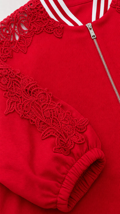 Close-up detail of red floral lace appliqué on sleeve and striped ribbed collar
