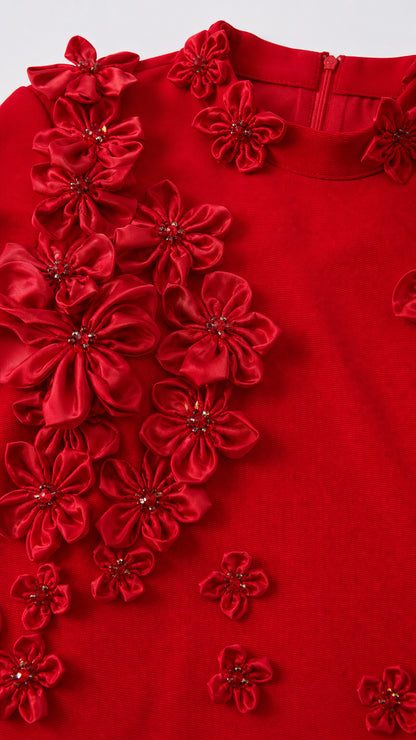 Close-up detail of red fabric flowers and beading on the gown