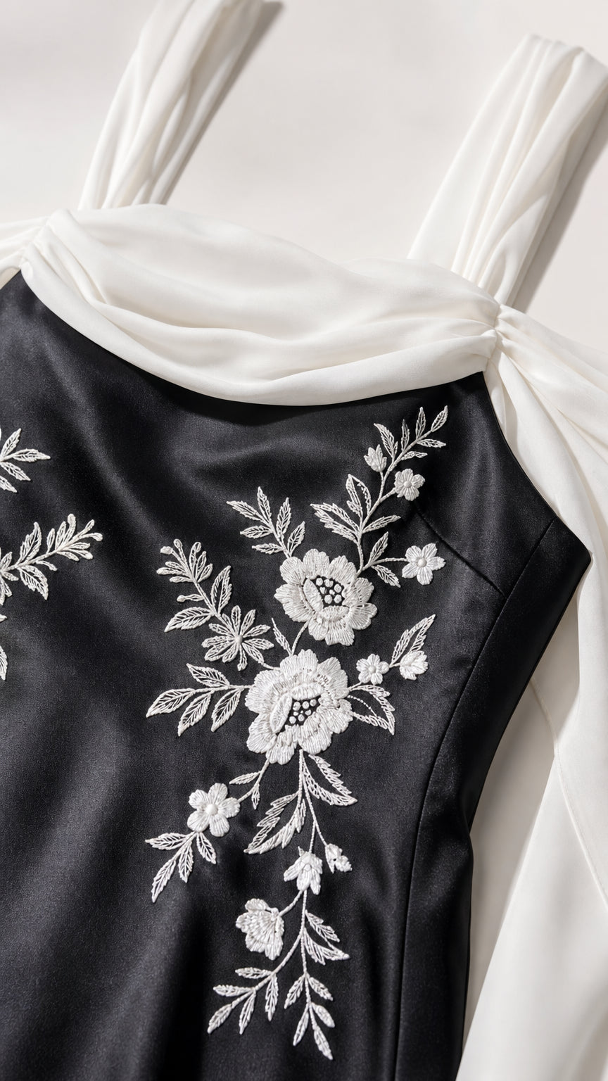 Close-up detail of white floral embroidery on black satin bodice