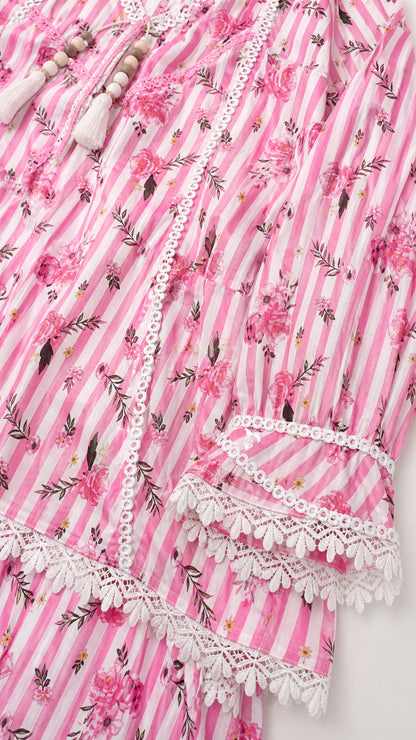 Close-up detail of pink tunic neckline, lace trim, and tassel ties