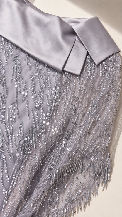 Close-up detail of silver satin folded lapel collar and sparkling sequin fringed embroidery