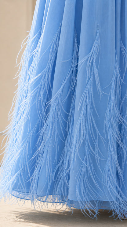 Close up of feather trim detail on the hem of the blue dress