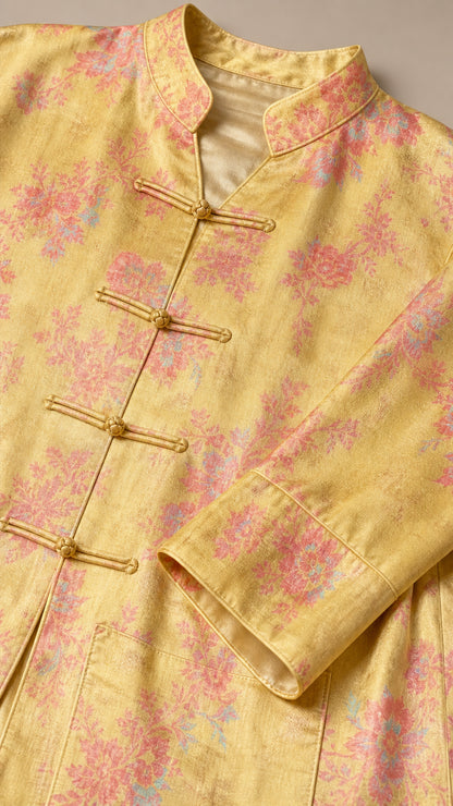 Close-up detail of yellow floral jacquard fabric with mandarin collar and frog knot buttons