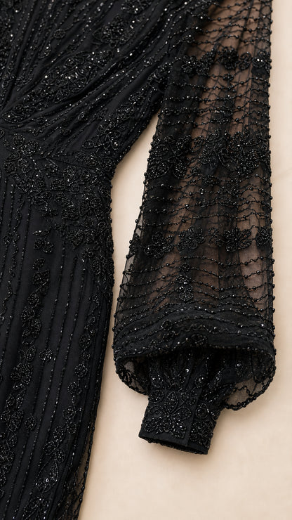 Close-up detail of black beadwork, sequin patterns, and bishop sleeve cuff