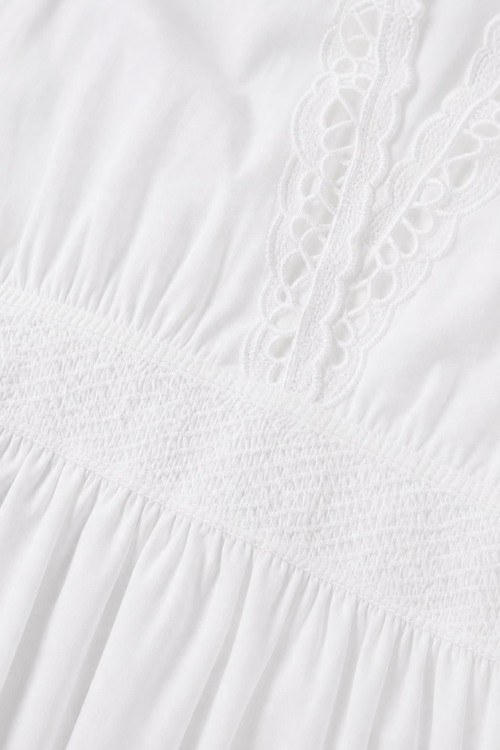 Close-up detail of white fabric, smocked waist, and lace trim