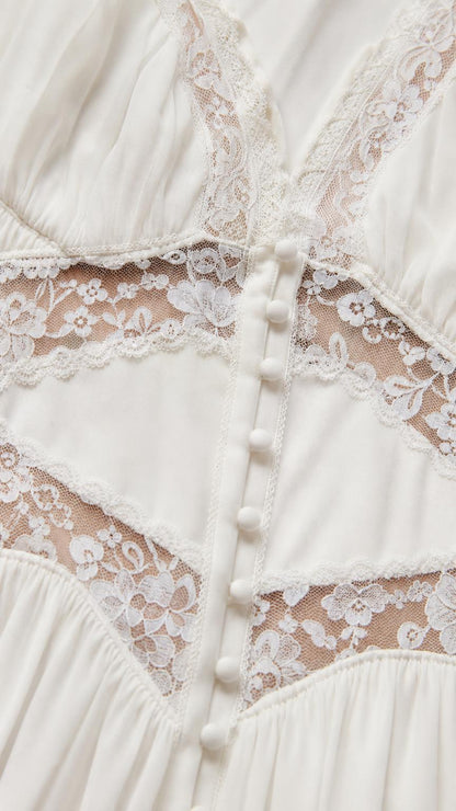 Close-up detail of lace inserts and front buttons on white dress