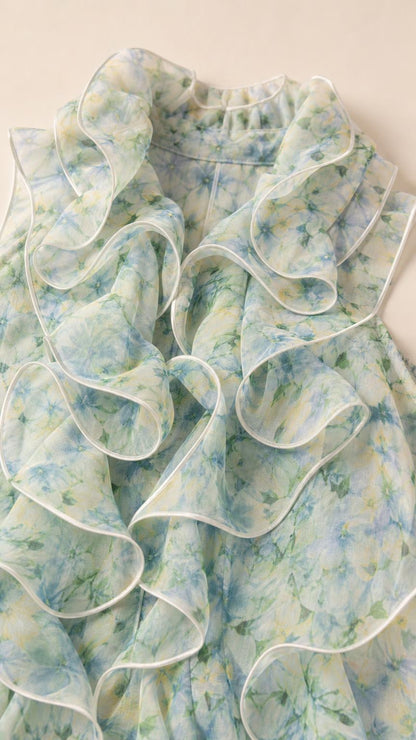 Close-up detail of light blue floral fabric and ruffled neckline