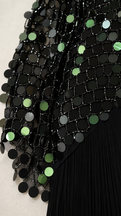 Close-up detail of black and green reflective sequin fabric