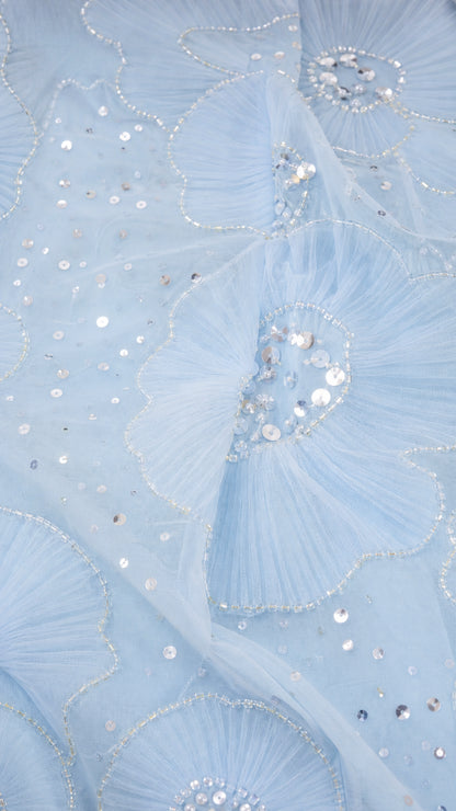 Close-up of light blue mesh fabric with sequin floral embroidery