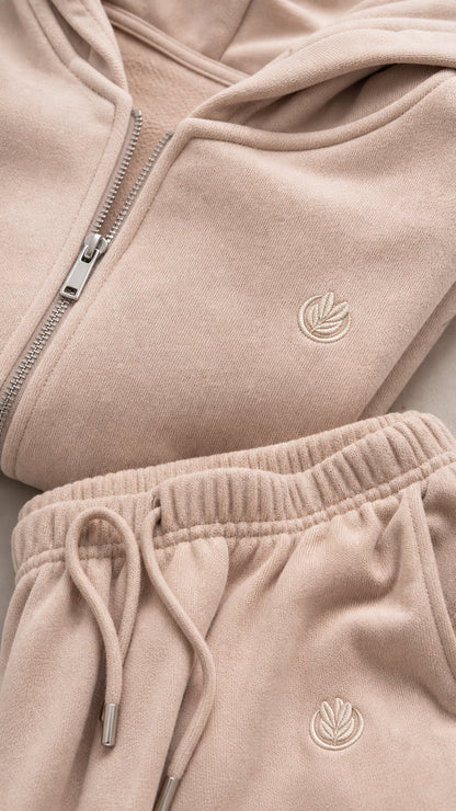 Close-up of beige hoodie zipper, hood, tonal detail, and drawstring pants