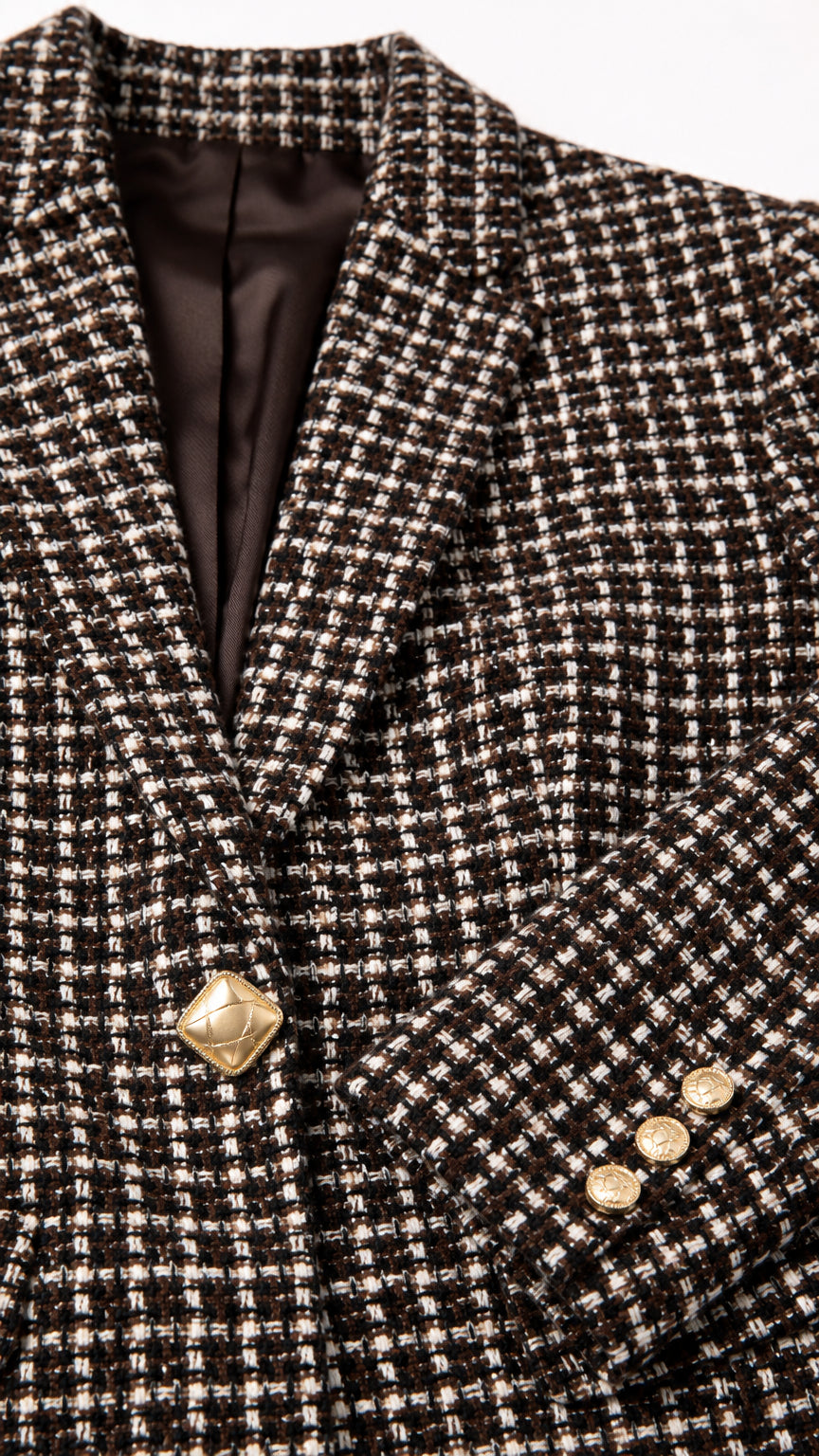Close-up detail of textured tweed lapel, gold button, and smooth lining