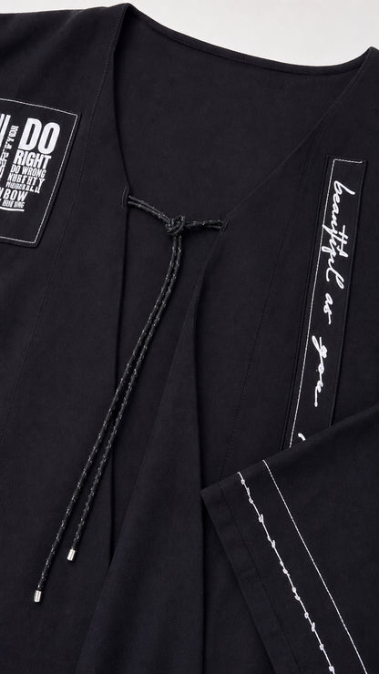 Close-up detail of V-neckline and text prints on black set