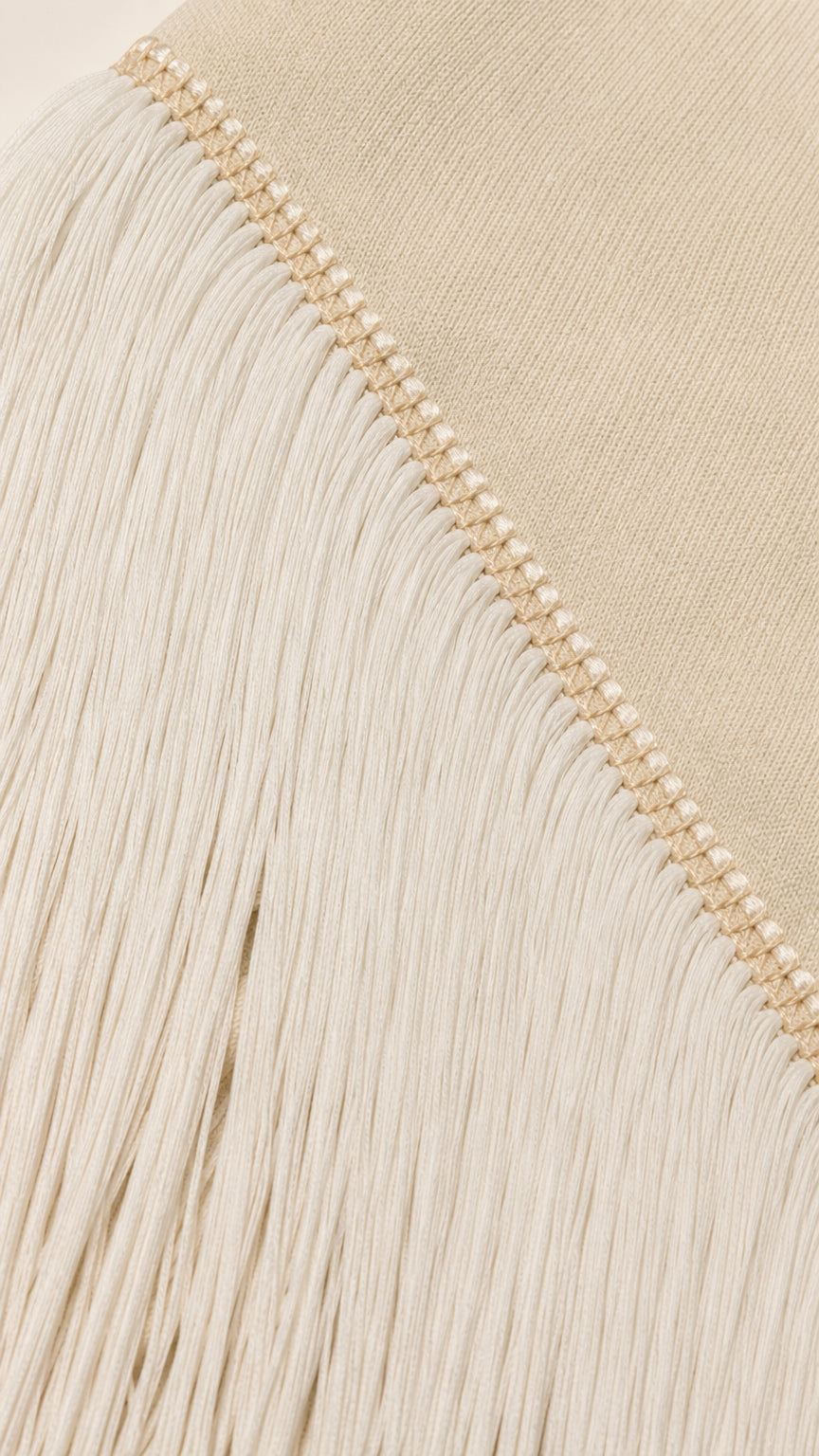 Close-up detail of cream fringe trim and knit texture