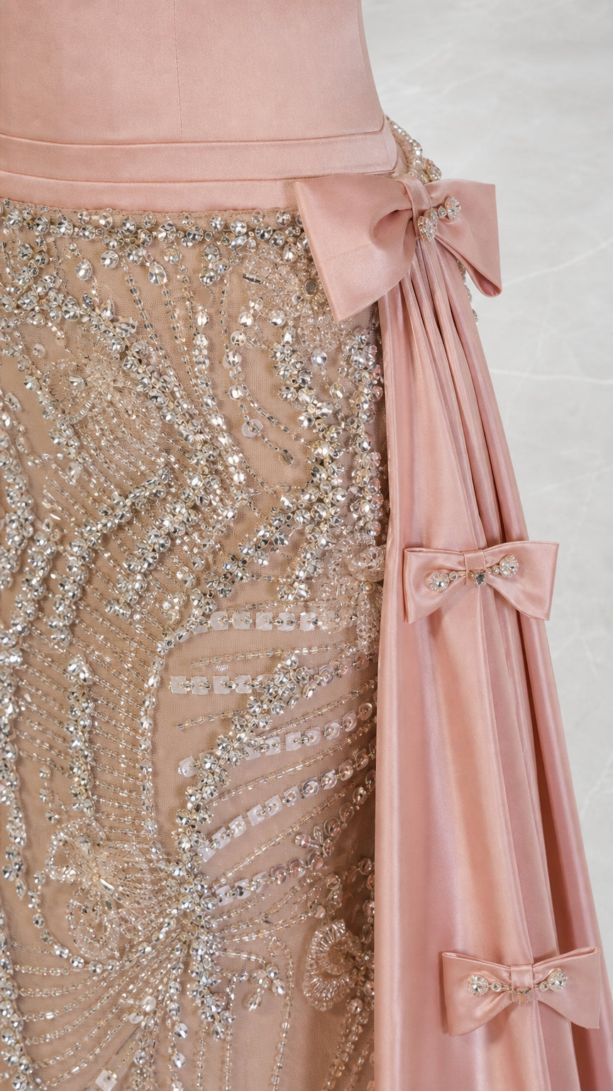 Close-up detail of sequin beadwork and bow accents on pink gown