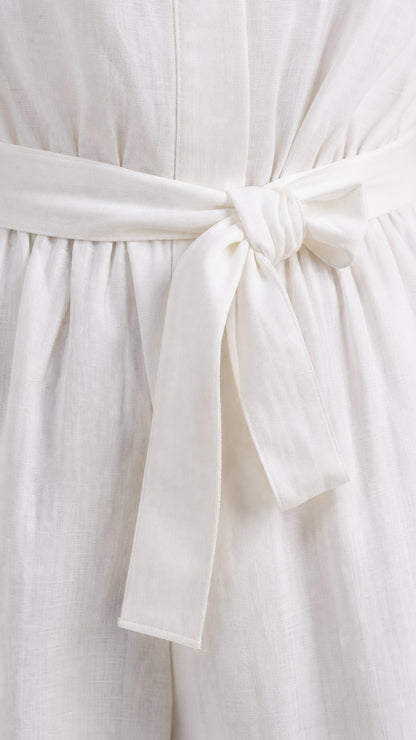 Close up view of white textured fabric and tied waist belt on jumpsuit
