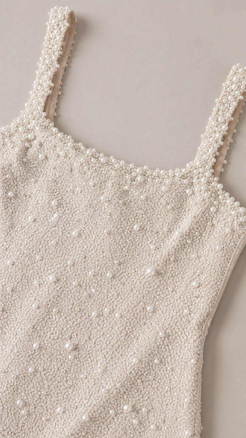 Close-up detail shot of ivory textured fabric with intricate faux pearl embellishments