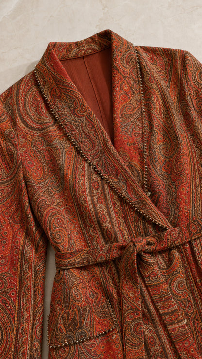 Close-up detail of rust paisley blazer with trim on shawl lapel and tie waist belt