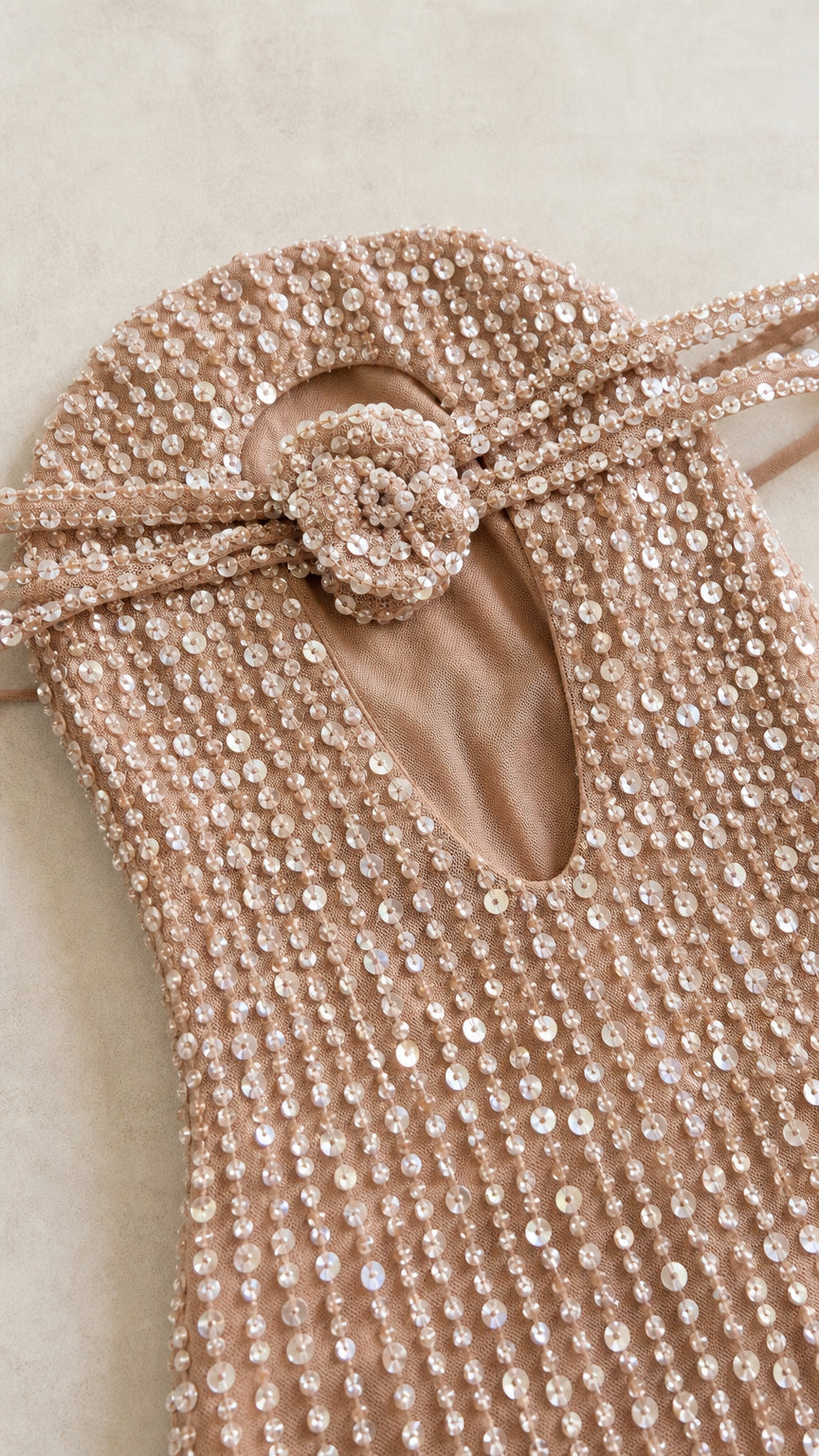 Close-up of champagne sequin gown bodice with 3D rosette and teardrop cutout