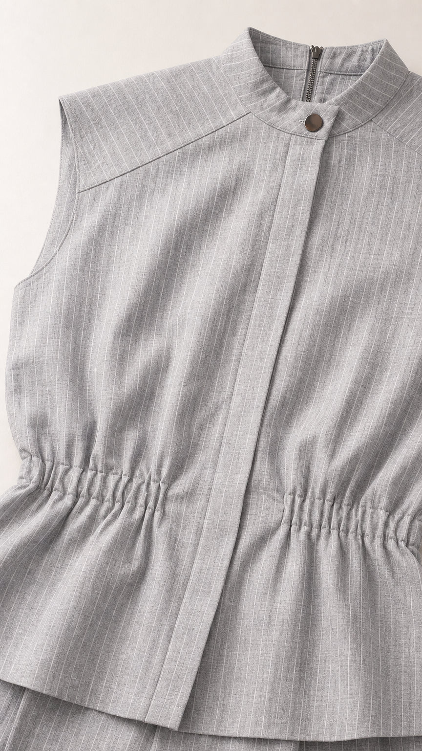 Close up of mock neck and cinched waist detail on light grey top
