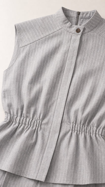 Close up of mock neck and cinched waist detail on light grey top