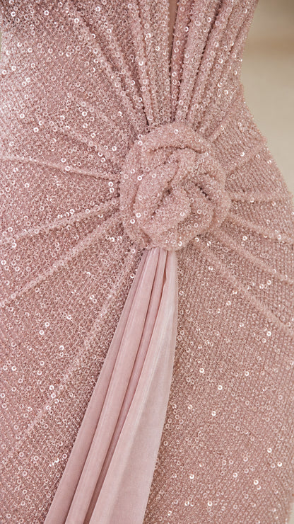Close-up detail of blush pink sequin fabric, waist rosette knot, and draped sash