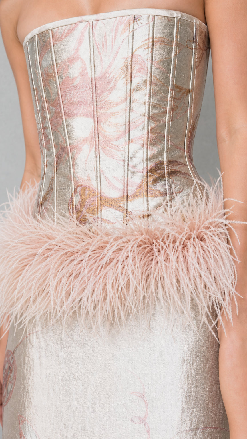 Close-up detail of structured boned corset bodice and blush feather waist trim