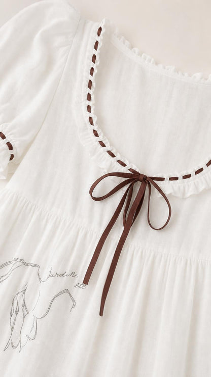 Close-up of neckline, ribbon tie, and embroidery details