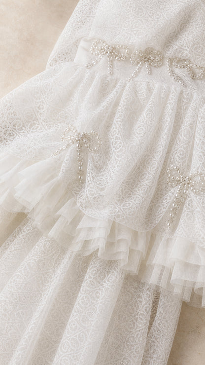 Close-up detail of rhinestone bow embellishments and ruffled lace texture